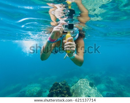 A young caucasian woman taking pictures under water.  Koh Tao, Thailand.