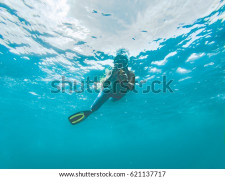 Young woman taking pictures under water. Koh Tao, Thailand.