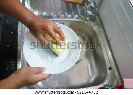 Close up hands of asian man washing dishes in kitchen.