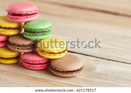 Green, pink, yellow and brown french macarons on the wooden boards, soft focus background