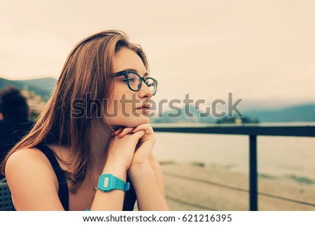 Nerdy cute girl in glasses Looking to the Mountain Landscape while sitting in restaurant. Toning. Traveling or Vacation Concept. Como, Italy