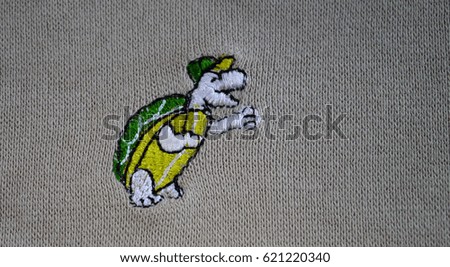 Machine embroidery. Embroidered turtle on gray fabric. Modern fashion design. Children's fashionable embroidery.