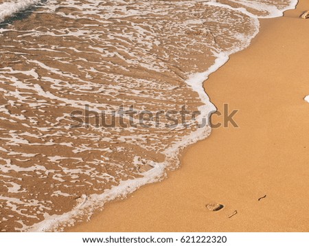 Sandy beach and waves, close-up. Texture of sand and water. Picture for the postcard. Vacation at sea. Advertising of the sea.