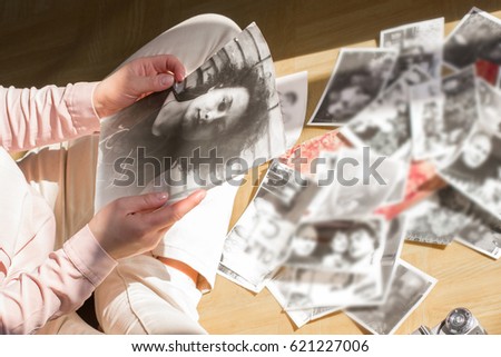 Young woman is sitting on the floor and looking at old photographs