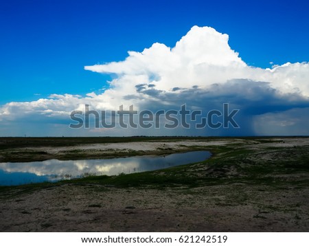 Looking at raining cloud from afar with blue sky background and water reflection during game drive in Chobe national park