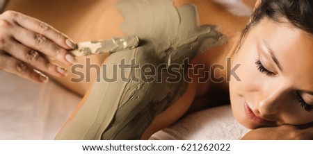 The girl enjoys mud body mask in a spa salon. Luxury treatment. Royalty-Free Stock Photo #621262022