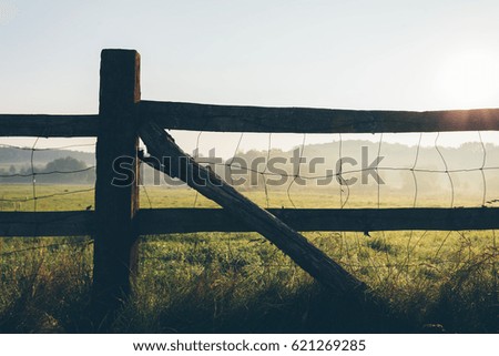 Old wooden rural fence on the field early in the morning