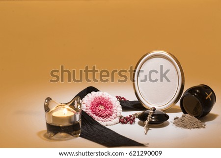 black urn with black tape, gerbera flower, candle, rosary for sympathy card on yellow background