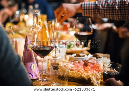 Restaurant or bar table with plates of appetizers and wine. People talking on background. Toned picture.