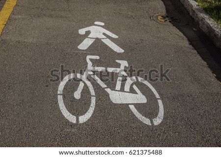 White painted bicycle way sign on asphalt in park.