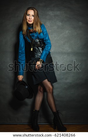 Steampunk and retro style. Attractive vintage woman with stylish accessories on dark background. Fashionable female portrait.
