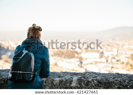Young woman tourist on the viewpoint, admiring the view of the mountains "Alps" and the city of Salzburg in Austria. Travel, vacation, tourism, attractions.