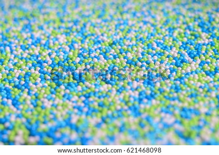 Background picture of a variety of colored glazed powder in the form of small balls. A huge number of sweet, colorful beads of very small size for decoration of pastry products