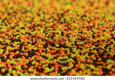 Background picture of a variety of colored glazed powder in the form of small balls. A huge number of sweet, colorful beads of very small size for decoration of pastry products
