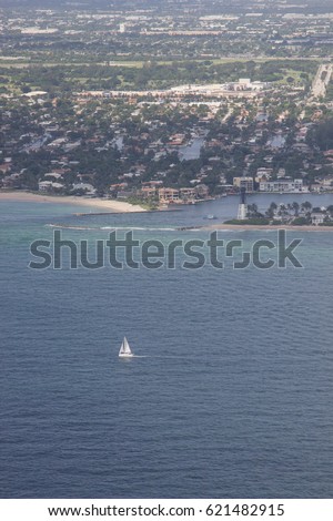 Aerial of sailboat sailing in front of Hillsboro lighthouse with city in background, Florida. 