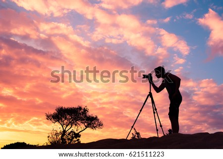 Outdoor and landscape photography concept. Photographer taking a picture of the sunset. 