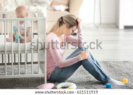 Depressed young woman with cute baby at home Royalty-Free Stock Photo #621511919