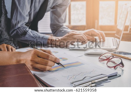 Image of two young business team using laptop computer and graph financia at meeting.Close up business team analysis and strategy concept.