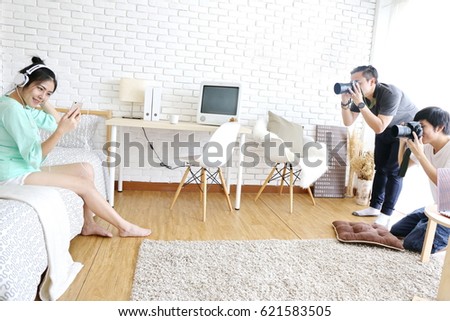 professional photographer take photo with Asian beautiful woman model with headphone on bed.