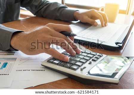 Financial Concept: Businessman working with calculator. Noise is visible from photo filter effect