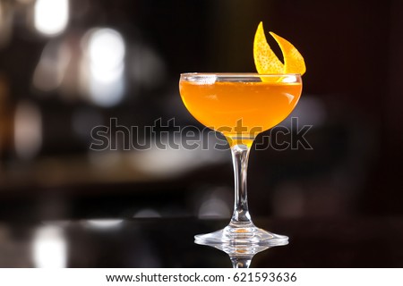 Glass of orange cocktail decorated with lemon at bar counter background. Royalty-Free Stock Photo #621593636