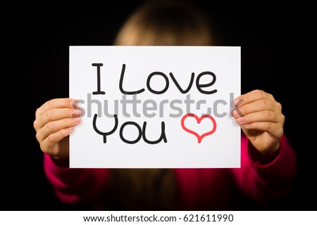 Studio shot of child holding an I Love You sign made of white paper with handwriting.