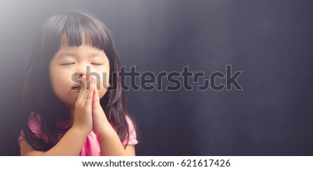 Little girl praying in the morning.Little asian girl hand praying,Hands folded in prayer concept for faith,spirituality and religion.Black background.pray for Texas.kid child girl with faith and trust