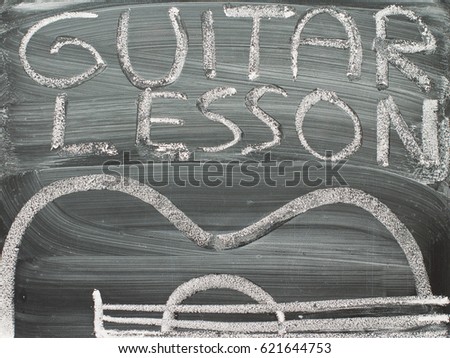 Guitar lesson, words on chalkboard with picture of acoustic instrument