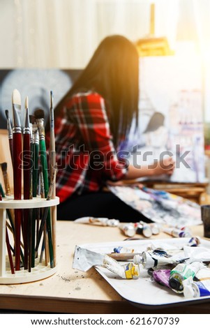 Long-haired brunette drawing on canvas in art workshop