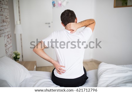 Man suffering from back pain at home in the bedroom. Royalty-Free Stock Photo #621712796