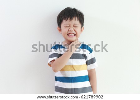 Little Asian boy with sore throat touching her neck, feeling pain in his throat. Royalty-Free Stock Photo #621789902