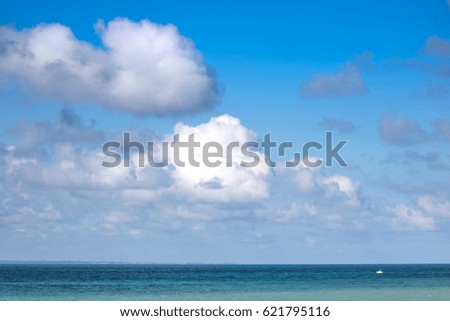 Snow-white clouds on the blue sky and azure sea.