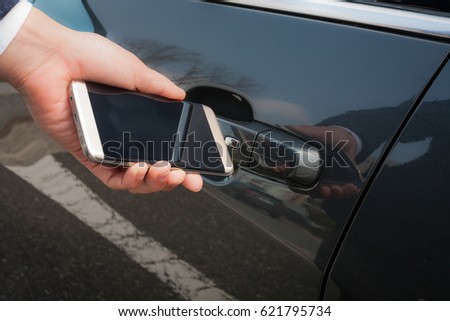 Opening and closing car door with smart phone / Automobile, IT, information communication Royalty-Free Stock Photo #621795734