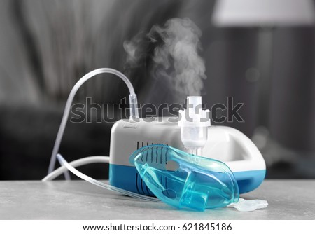 Compressor nebulizer with mask on table Royalty-Free Stock Photo #621845186