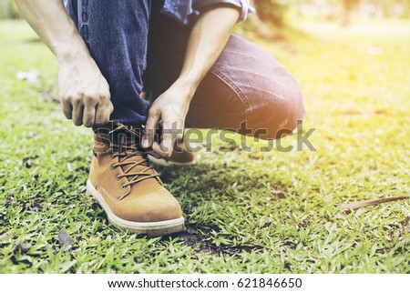 Young man binding shoes on thr grass, Vintage style photo.