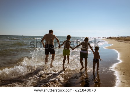 Happy children playing and splashing in the sea beach. Kids having fun outdoors. Summer vacation and healthy lifestyle concept.