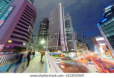 Evening view of a pedestrian footbridge over a busy street with high rise office towers under blue twilight in background in Shinjuku, Tokyo, Japan ~ Beautiful scenery of Tokyo Downtown at rush hour