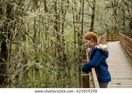 A stands against the railing of the Muddy Creek Boardwalk in the William L Finley National Wildlife Refuge. Royalty-Free Stock Photo #621859298