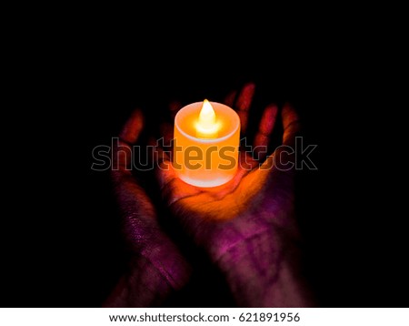 Candle in women hands on black background