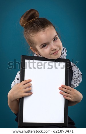Isolated on blue, beautiful caucasian brunette child hold empty poster, look at camera, stand behind the poster