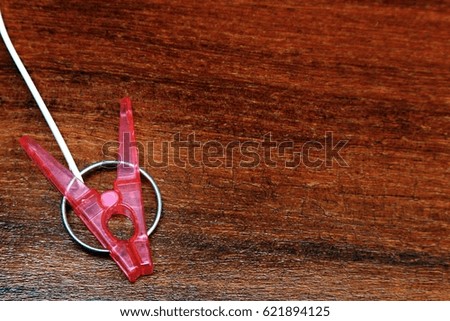 Red plastic clothespin on wood background with selective focus