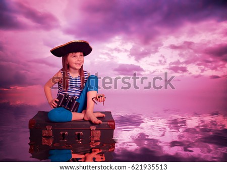 Child floats on a suitcase at the sunset on the sea.