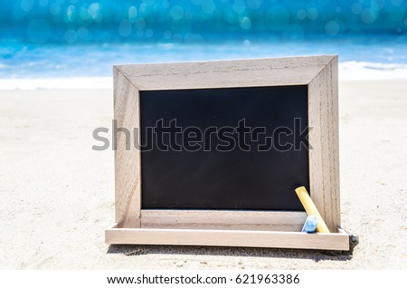 Empty black wood board with chalk on the sandy beach near the ocean