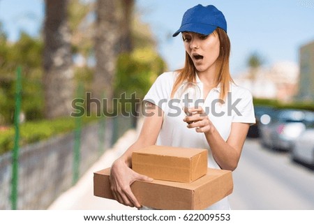 Surprised Delivery woman holding a bulb on unfocused background
