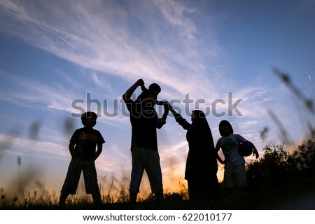 Silhouette children with parents playing on  sunset summer meadow