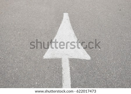 surface old and pale white painted arrow sign on cement road textured background