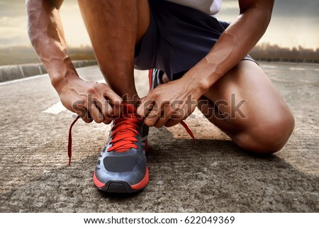 Man tying running shoes Royalty-Free Stock Photo #622049369
