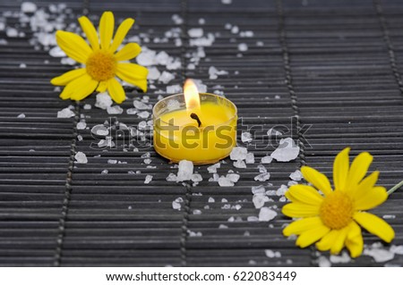 Yellow gerbera daisy with candle ,pile of salt on mat