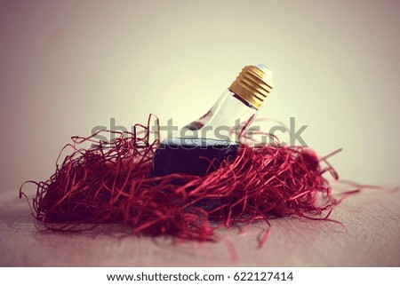 Bulb with blue liquid inside pose in red shredded paper.