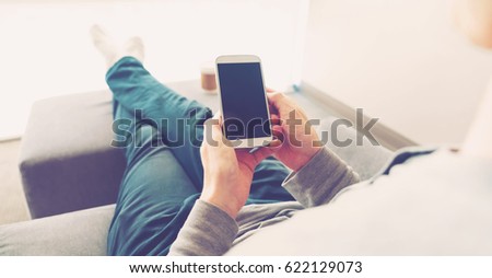 Over the shoulder view of person relaxing while using smart phone